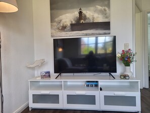 A flat-screen TV mounted on a white entertainment center with a framed picture above it. - Vacation farm at Fischland Flügge (Wustrow)