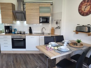A modern kitchen with a built-in oven, microwave, and stainless steel range hood. - Vacation farm at Fischland Flügge (Wustrow)