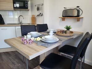A modern kitchen with white cabinets, a microwave, and a toaster on a wooden shelf.