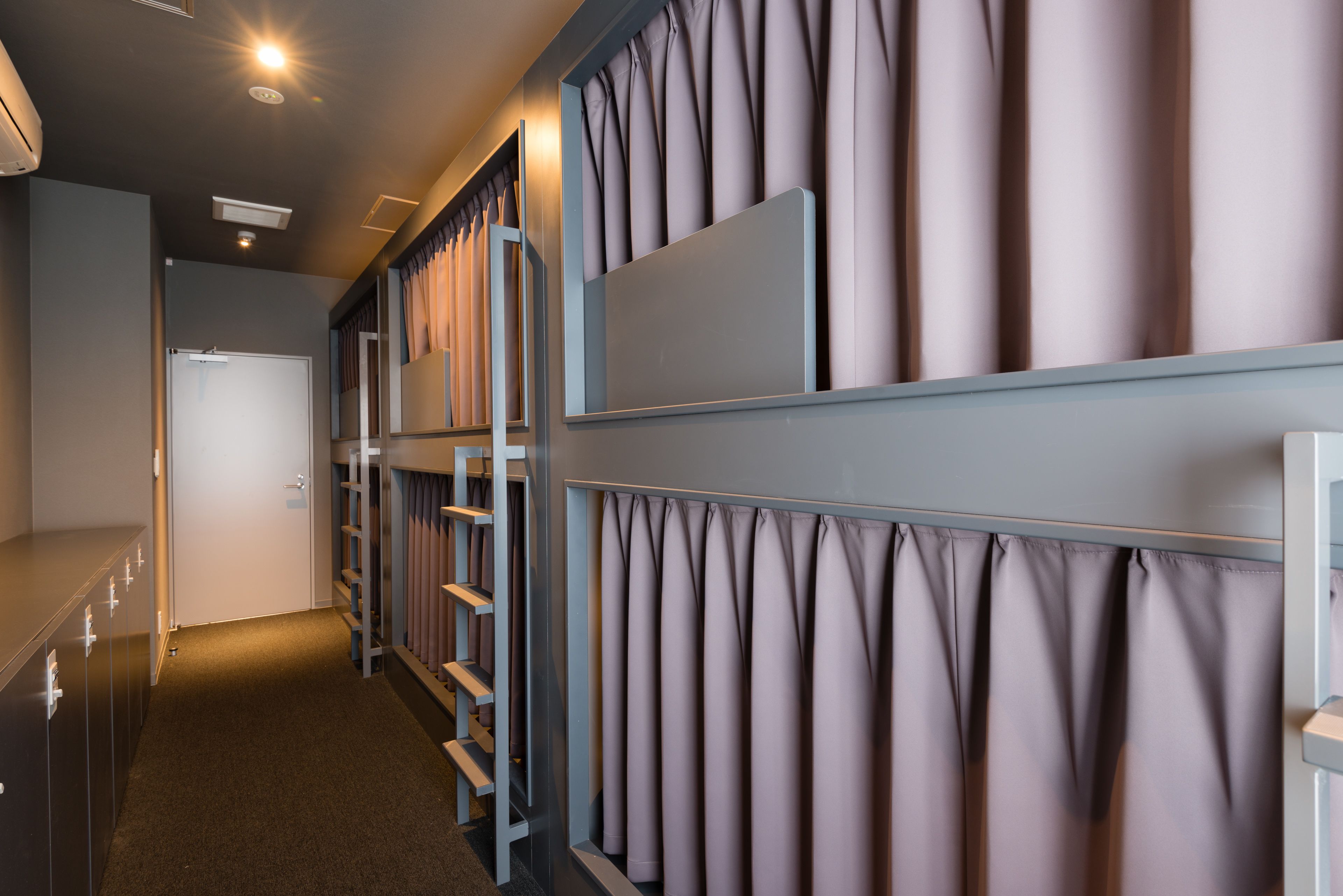 A hotel corridor with a row of rooms, each with a window and a curtain.