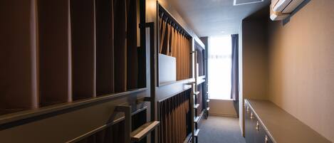 A hallway with a radiator, a window with curtains, and a wall-mounted air conditioner.