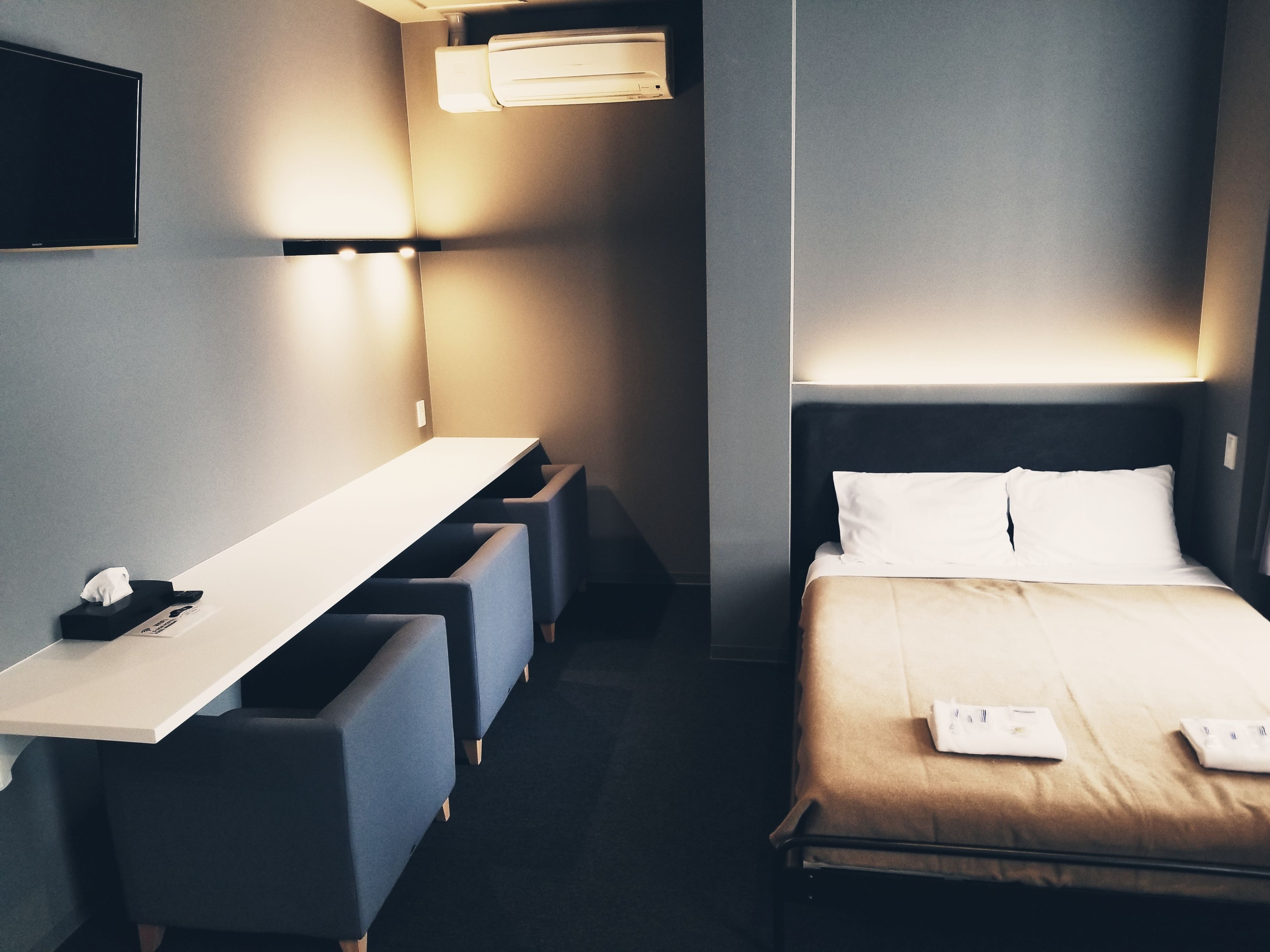 A hotel room with a bed, a desk, and a chair.