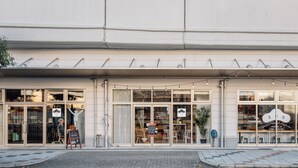 A hostel with large windows, a signboard, and outdoor seating. - BON Hostel (Osaka)