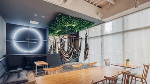 A modern meeting room with a wooden table, chairs, a sofa, and a wall-mounted hammock. - BON Hostel (Osaka)