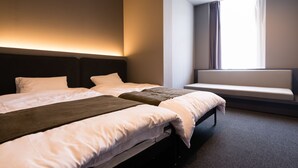 A modern hotel room with two beds, a bench by the window, and a wall-mounted light fixture. - BON Hostel (Osaka)