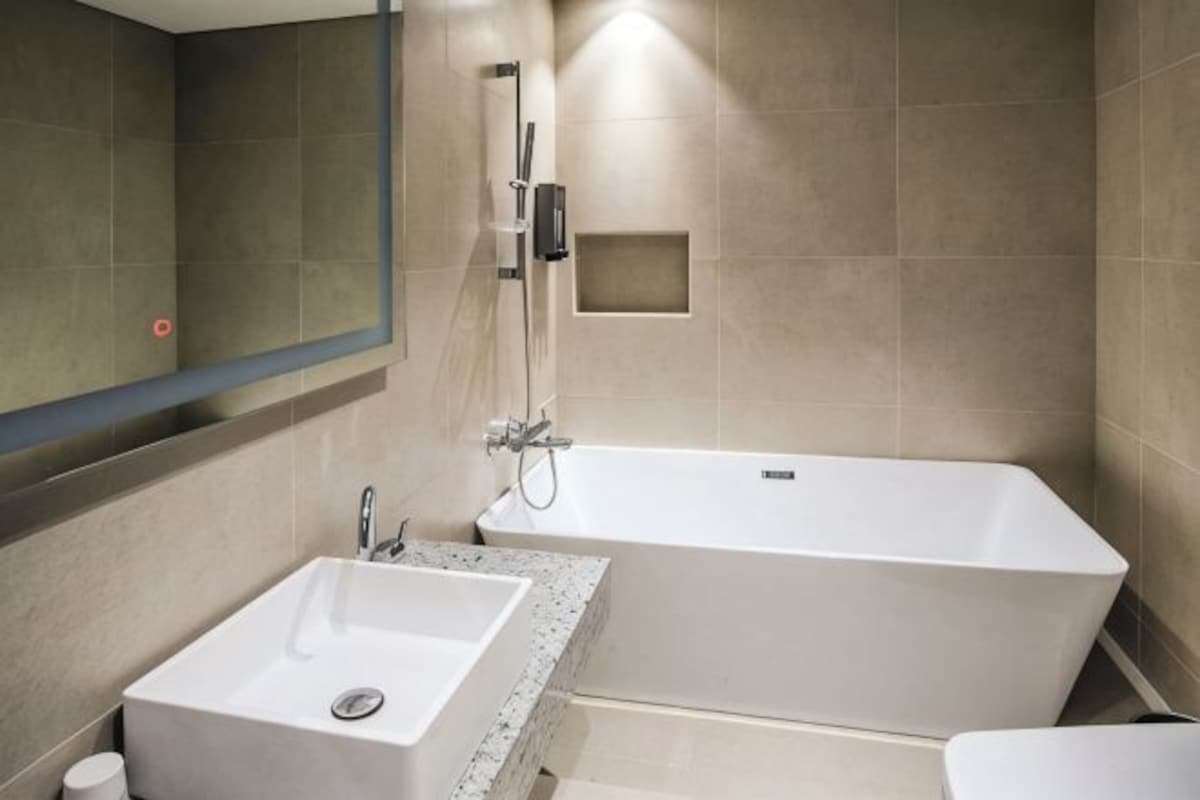 A bathroom with a rectangular bathtub, a sink, and a mirror.