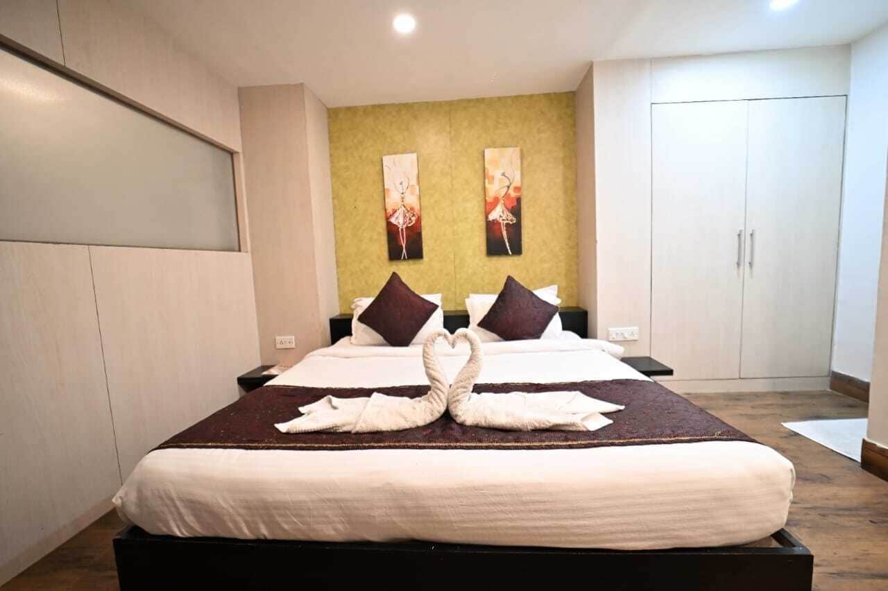 Una habitación de hotel con una cama grande, dos cuadros en la pared y un armario.