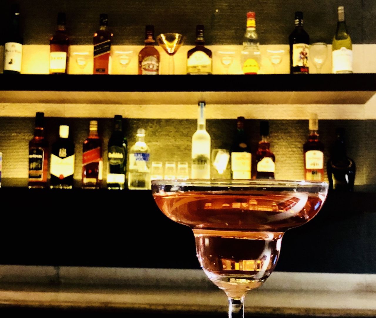 A bar with a variety of liquor bottles on shelves behind a glass.