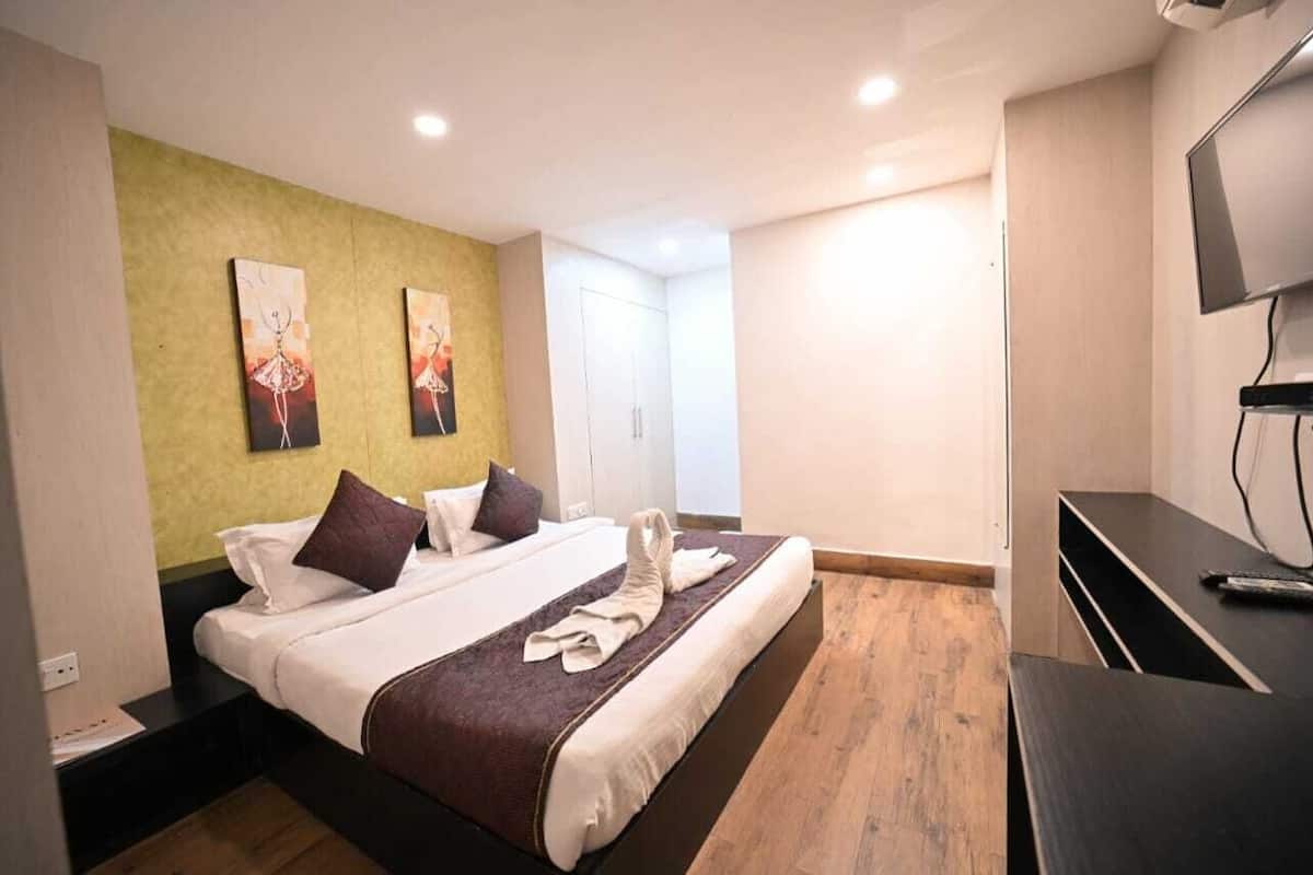 Una habitación de hotel con una cama grande, un escritorio, un televisor y obras de arte en la pared.
