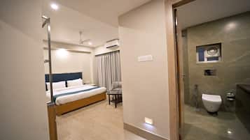 A modern hotel room with a bed, bedside table, and a bathroom with a toilet and shower.