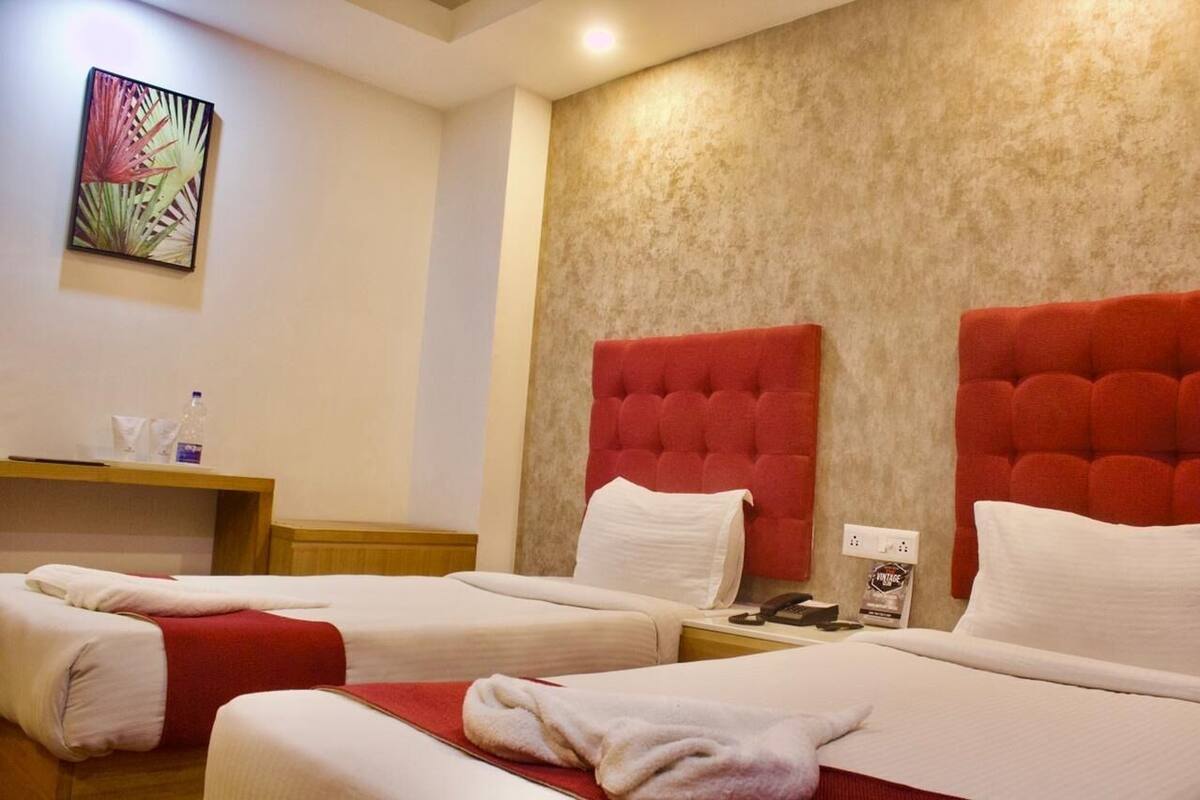 Habitación de hotel con dos camas, una mesita de noche de madera, un cuadro colgado en la pared y una pared con textura.