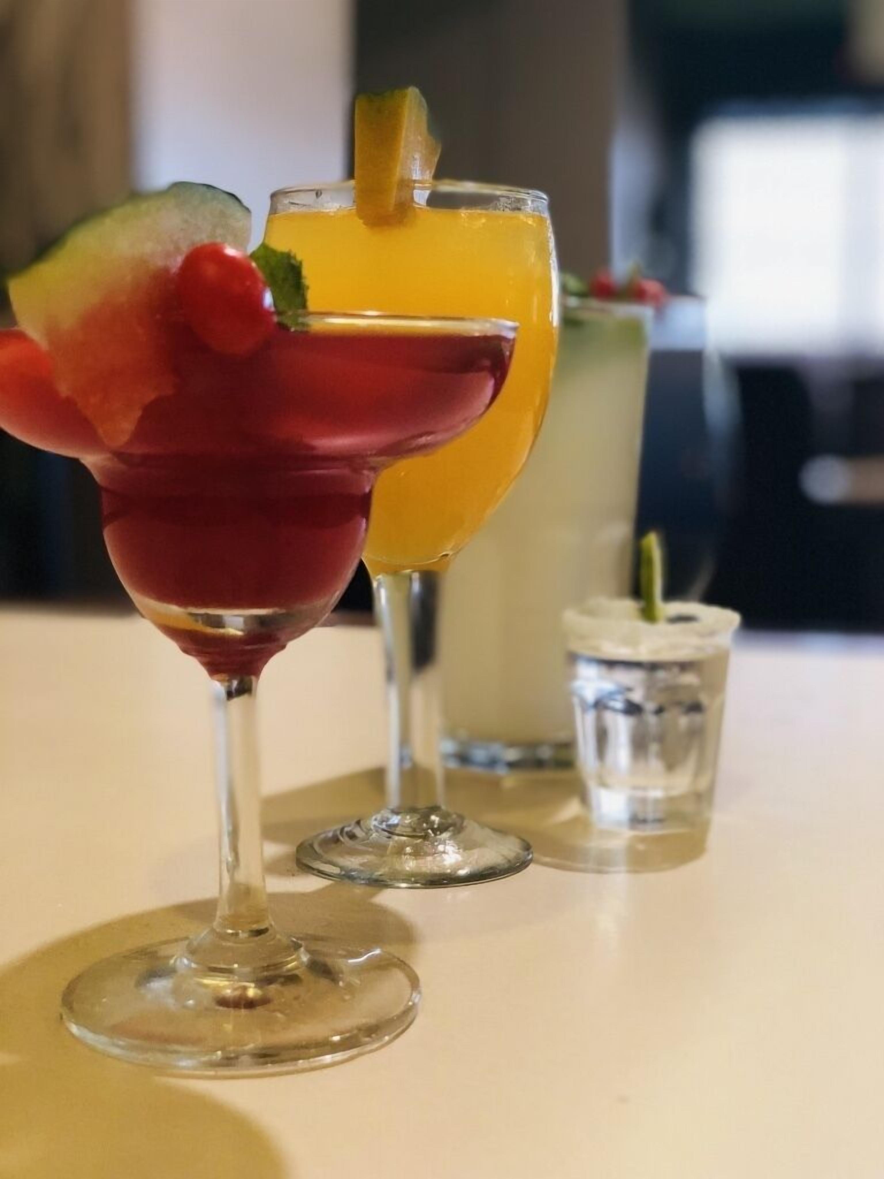 Two cocktails with garnishes on a table.