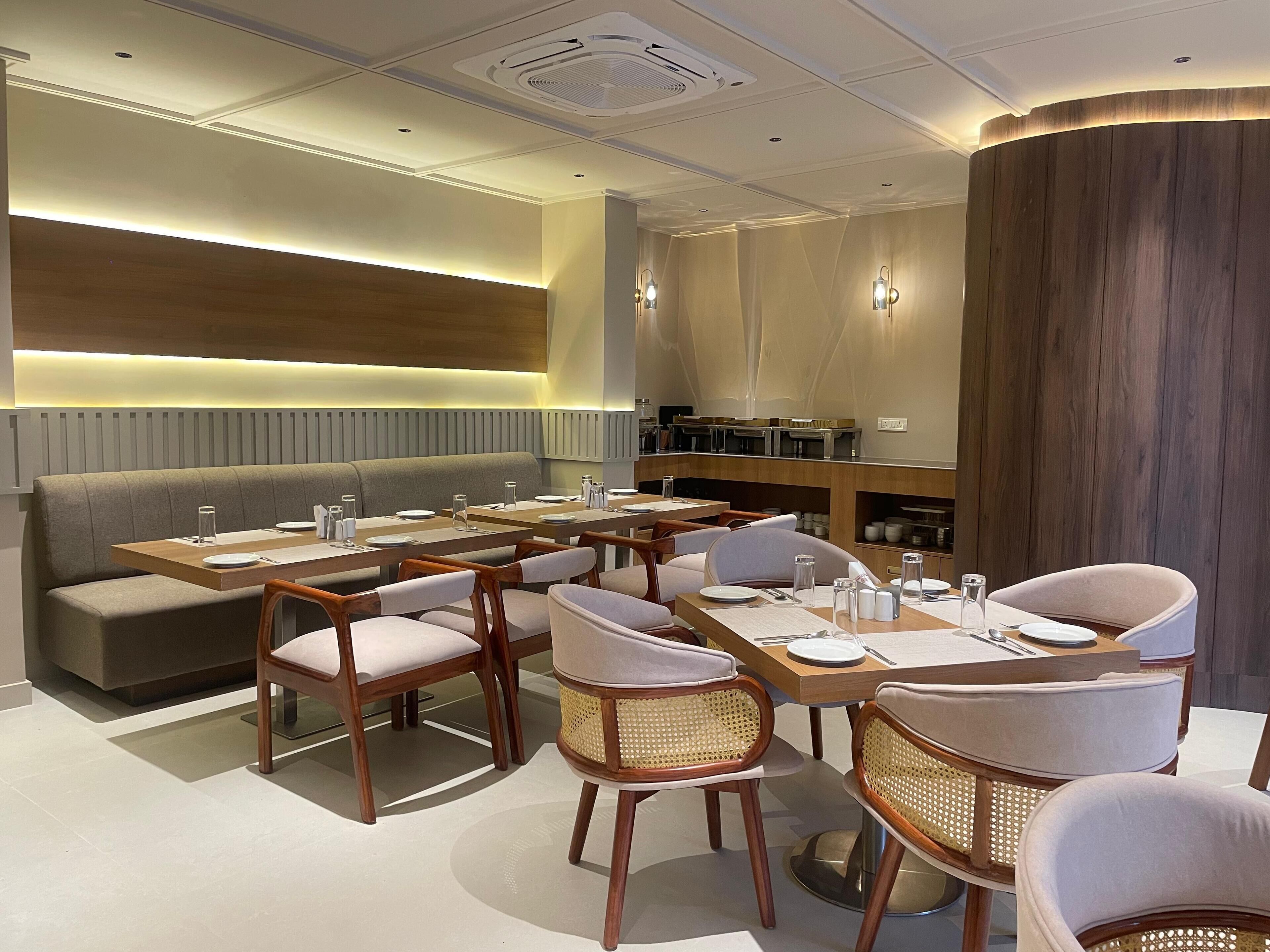 A modern dining area with a long table set for multiple guests, cushioned seating, and a wooden accent wall.