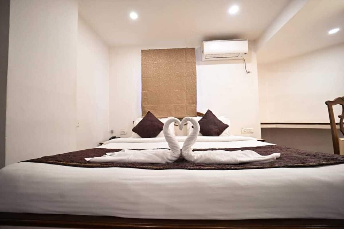 Una habitación de hotel con una cama bien hecha, un cabecero de madera y un aire acondicionado de pared.