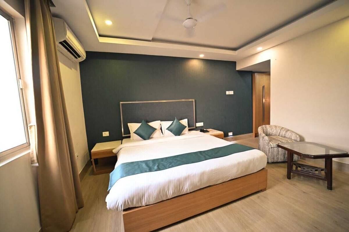 Una habitación de hotel moderna con una cama grande, mesitas de noche, una silla y una pequeña mesa.