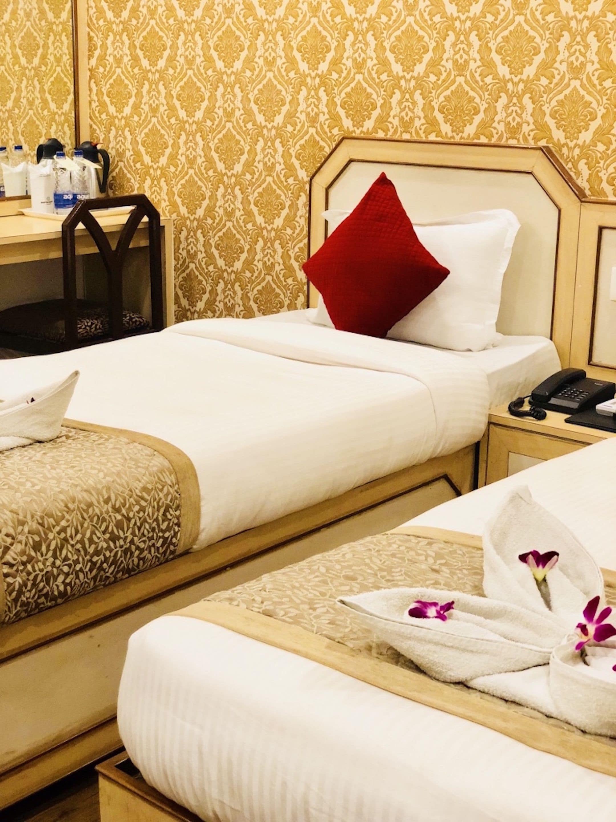 A hotel room with two beds, a desk, and a telephone.
