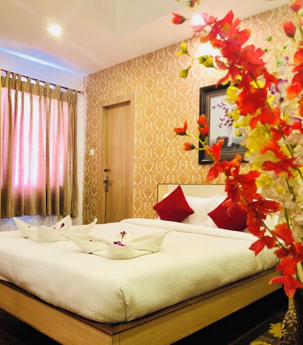 A hotel room with a neatly made bed, a door, and a patterned wall.