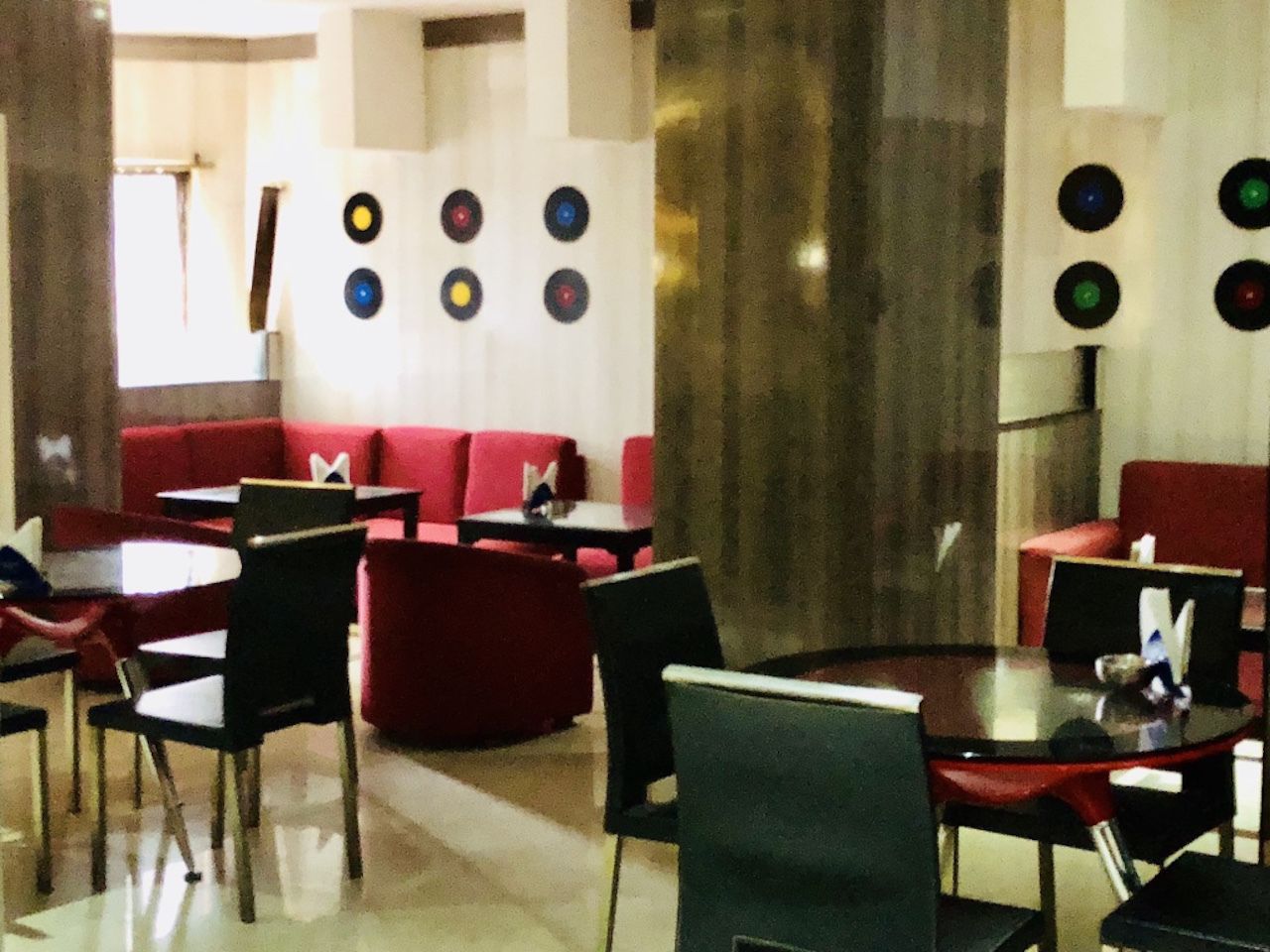 A restaurant with red booths, black and white chairs, and a wall decorated with circular patterns.