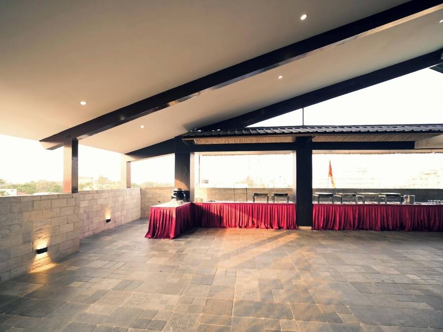 An outdoor patio with stone flooring, red tablecloths, and a view of the city skyline.