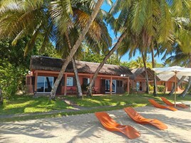 Un resort con edificios de techo de paja, mobiliario exterior y palmeras.