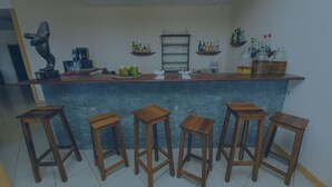 A bar area with a counter, stools, shelves with bottles, and a sculpture.
