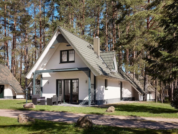 A two-story house with a sloped roof, a covered porch, and a large window.