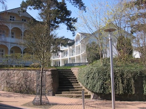 A building with a stone wall, a metal fence, and a staircase leading to a second floor.