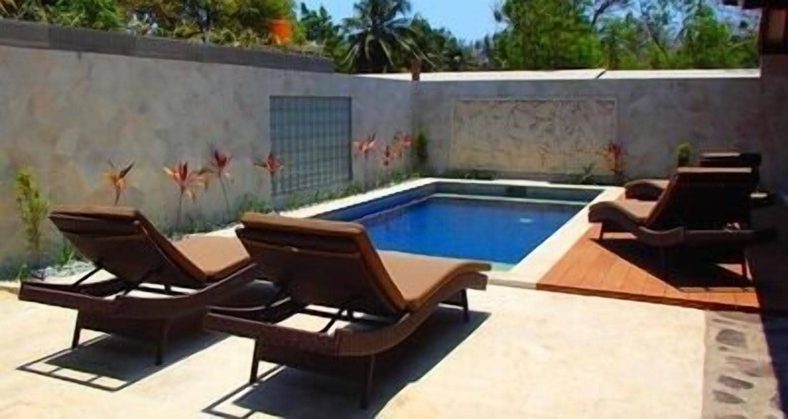 A swimming pool with lounge chairs and a tiled deck.