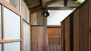 Een smalle houten gang met tatami vloeren en een traditionele Japanse poort aan het einde.
