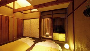 Een traditionele Japanse kamer met tatami vloerbedekking, schuifdeuren en een laag houten plafond.