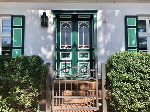 A green door with a white trim, a metal gate, and a brick wall. - Apartment Hinz - Apartment Hinz (Wustrow)