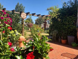 A garden with a pergola, potted plants, and a decorative sculpture. - Apartment Hinz - Apartment Hinz (Wustrow)
