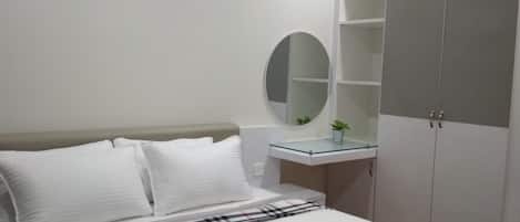Een slaapkamer met een bed, nachtkastje, spiegel en garderobe.