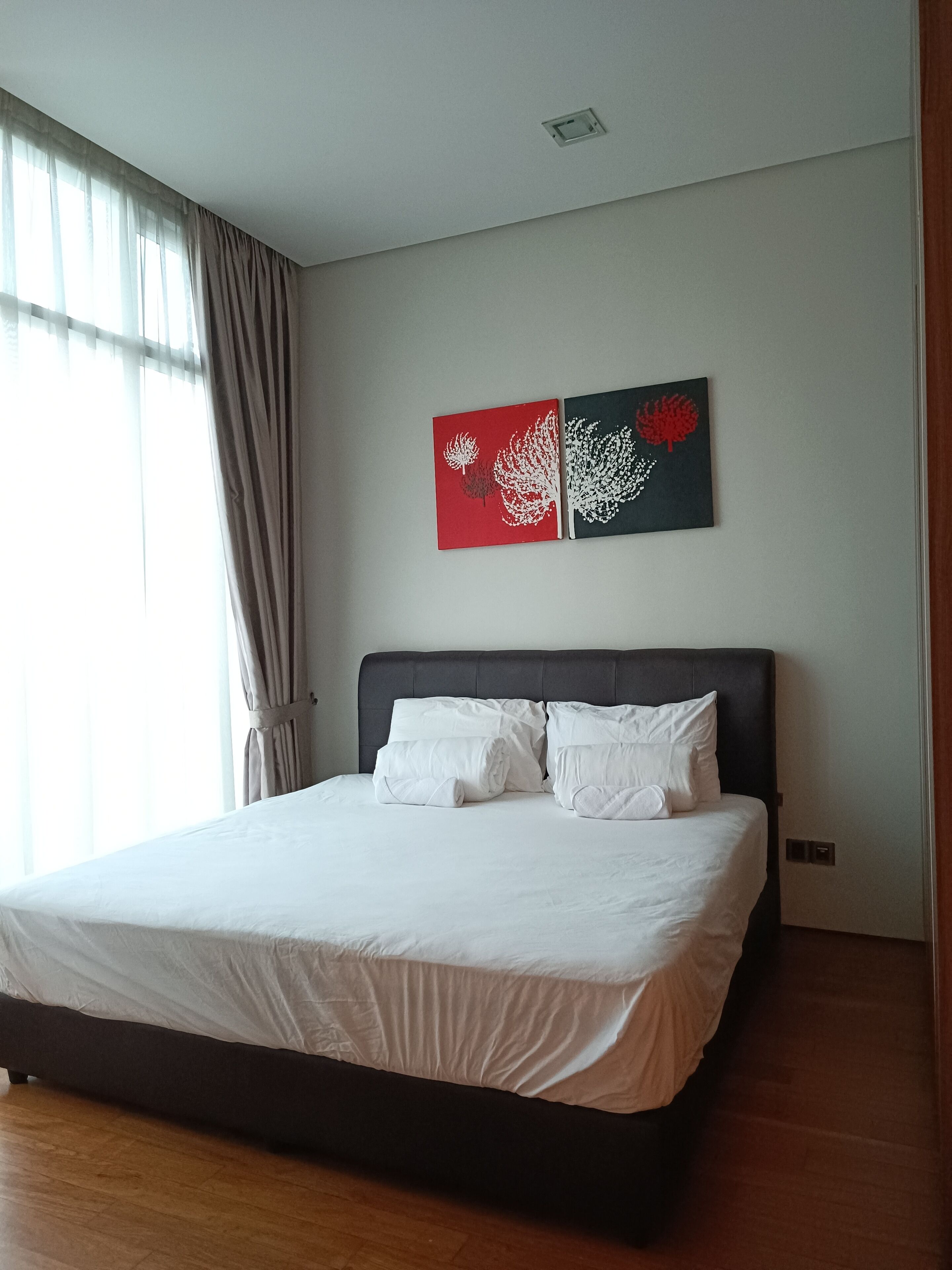 A bedroom with a large bed, a headboard, and two wall art pieces.