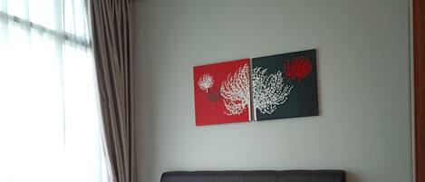 A bedroom with a large bed, a headboard, and two wall art pieces.