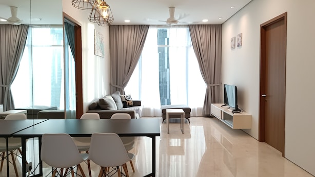 A modern living room with a dining area, large windows, and a flat-screen TV.