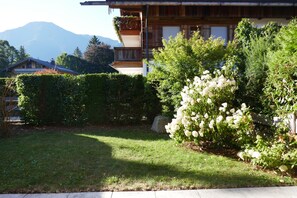 A wooden house with a balcony, surrounded by lush greenery and a mountain in the background. - Bodenschneid Suites Rottach-Egern - Bodenschneid Suites Wallbergblick (Rottach-Egern)