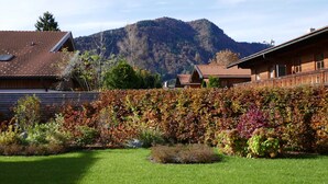 A residential area with a mountain in the background, a well-maintained garden, and houses with red-tiled roofs. - Bodenschneid Suites Rottach-Egern - Bodenschneid Suites Wallbergblick (Rottach-Egern)
