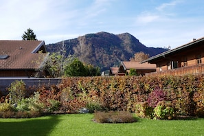 Ein Wohngebiet mit einem Berg im Hintergrund, einem gepflegten Garten und Häusern mit roten Ziegeldächern.