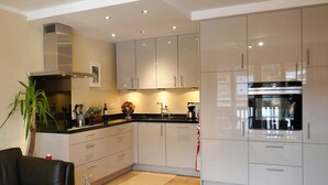 A modern kitchen with white cabinets, a black countertop, and a stainless steel oven. - Bodenschneid Suites Rottach-Egern - Bodenschneid Suites Wallbergblick (Rottach-Egern)