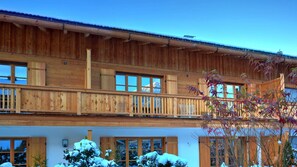 Un edificio de madera de varios pisos con balcones, ventanas amplias y un paisaje nevado.
