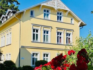 Un bâtiment à deux étages, avec une façade jaune et des ornements blancs.