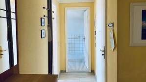 Un couloir avec un banc en bois, une porte dotée d’une poignée dorée et un tableau encadré accroché au mur.