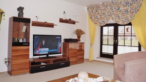 Ein Wohnzimmer mit einer Holzunterhaltungsecke, einem Flachbildfernseher und einem Fenster mit gelben Vorhängen.