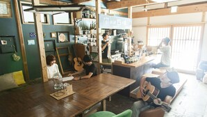 A rustic interior with wooden beams, a long table, and a green chair. - Fukuoka Guesthouse HIVE - Hostel (Fukuoka)