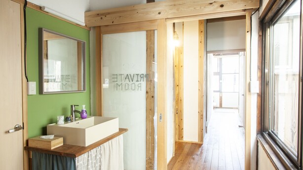 A bathroom with a wooden vanity, a mirror, and a glass shower enclosure. - Fukuoka Guesthouse HIVE - Hostel (Fukuoka)