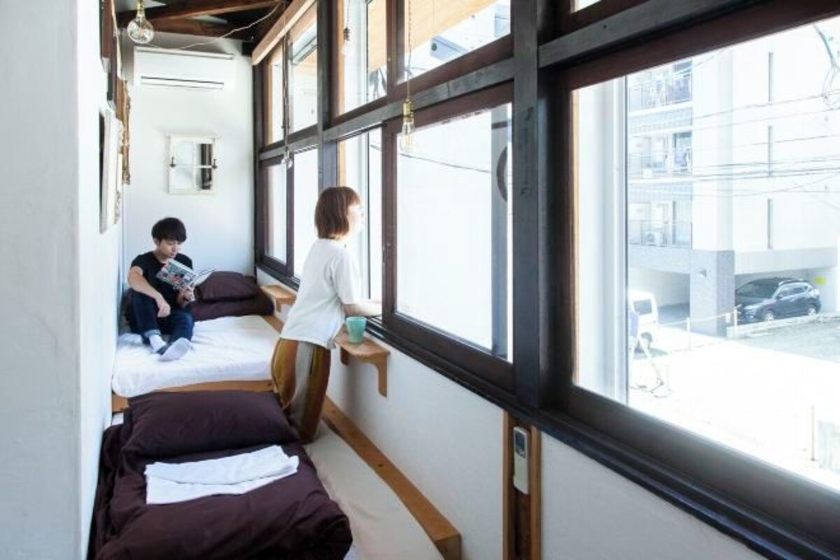 Une chambre avec deux lits, une fenêtre et une vue sur l’extérieur.