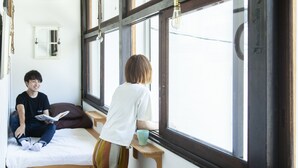 A room with two beds, a window, and a small table. - Fukuoka Guesthouse HIVE - Hostel (Fukuoka)