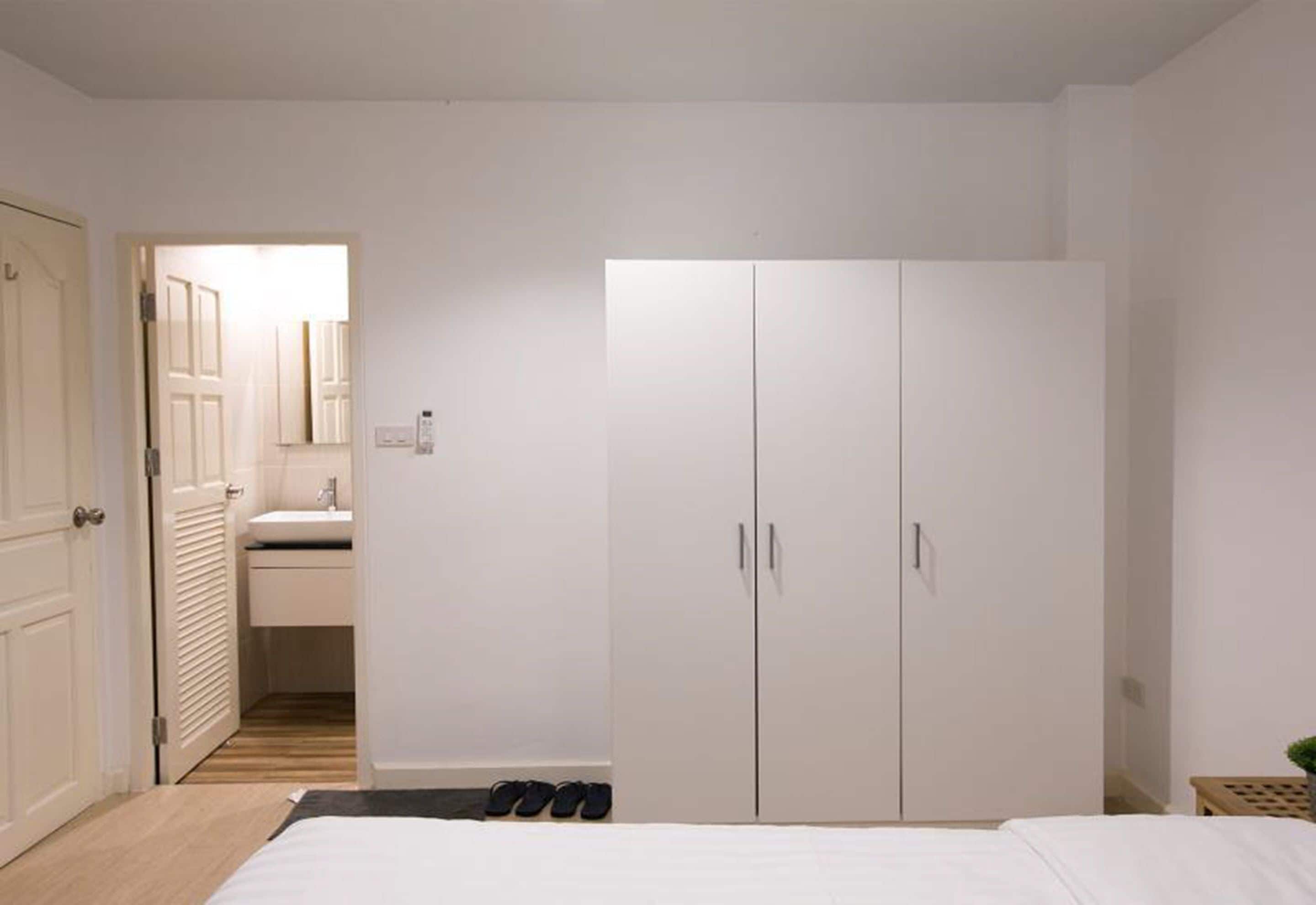 Een slaapkamer met een bed, een kledingkast, een spiegel en een deur naar een badkamer.
