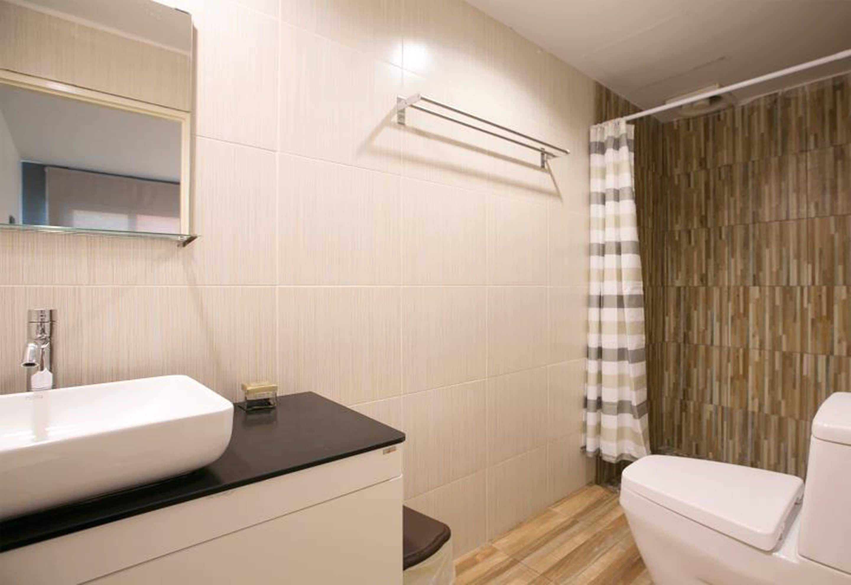 Un baño con lavamanos blanco, un espejo, toallero, inodoro y cortina de ducha.